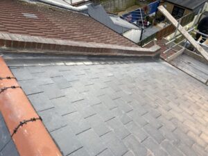 New ridge line tiles and chimney lead flashing installed on a roof