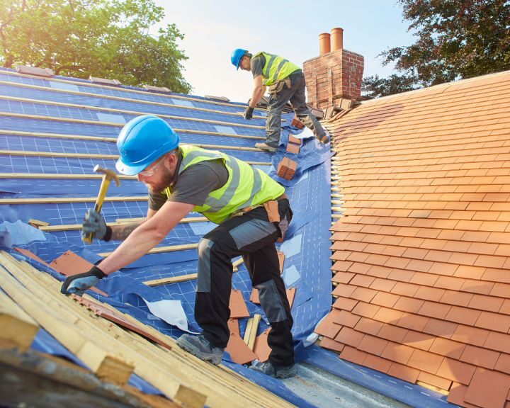 Two roofing contractors installing a new pitched roof on a residential property