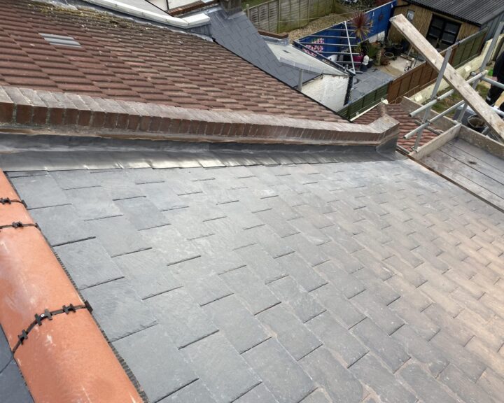 New ridge line tiles and chimney lead flashing installed on a roof